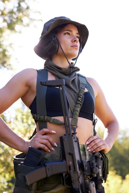 Foto porträt der jungen frau mit der waffe in der militärkleidung im freien