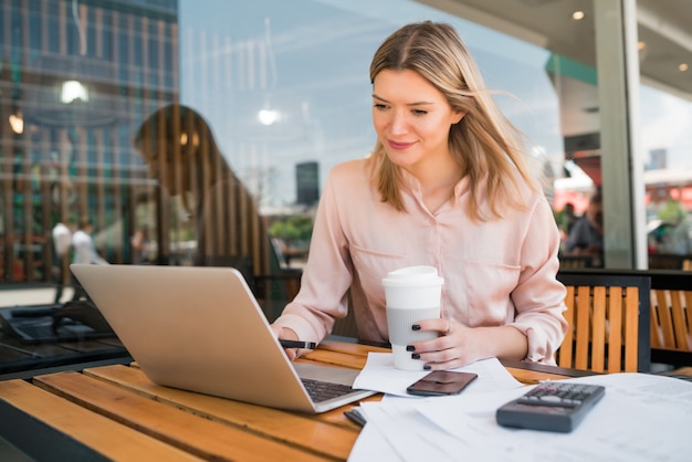 Porträt der jungen Geschäftsfrau, die an ihrem Laptop in einem Café arbeitet. Unternehmenskonzept.