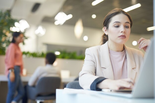 Porträt der jungen Geschäftsfrau, die Laptop während der Arbeit im Café verwendet