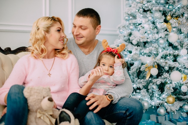 Porträt der jungen glücklichen Familie nahe Weihnachtsbaum