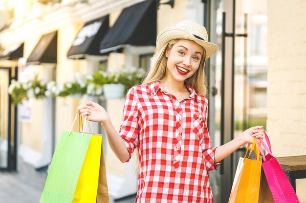 Porträt der jungen glücklichen lächelnden Frau. Junge Frau, die Einkaufstaschen hält. Online-Shopping-Konzept.