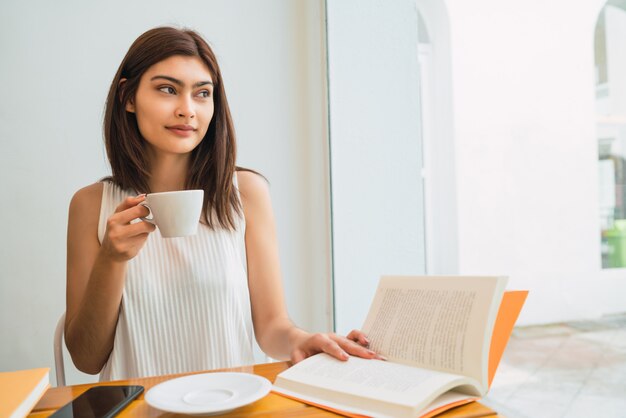 Porträt der jungen lateinamerikanischen Frau, die eine Tasse Kaffee am Kaffeehaus genießt und trinkt. Lifestyle-Konzept.