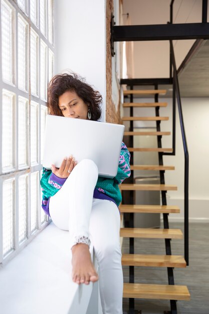 Porträt der jungen lateinamerikanischen Frau, die mit ihrem Laptop zu Hause arbeitet. Platz für Text.