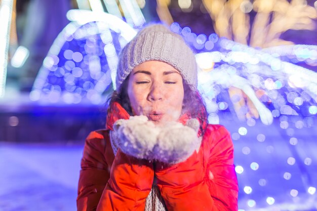 Porträt der jungen lustigen attraktiven Frau über schneebedeckten Weihnachtshintergrundwinterferien und -saison