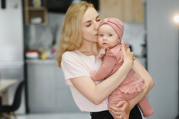 Porträt der jungen Mutter mit süßem Baby zu Hause