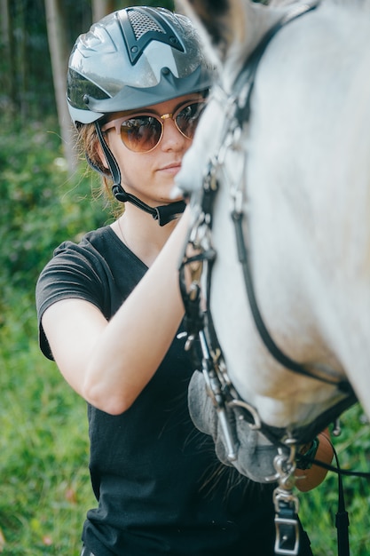 Porträt der jungen netten Frau mit Pferd am Sommer