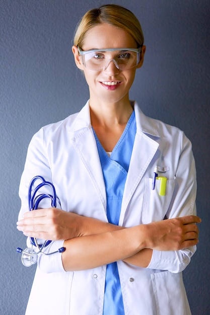 Porträt der jungen Ärztin mit weißem Mantel, der im Krankenhaus steht