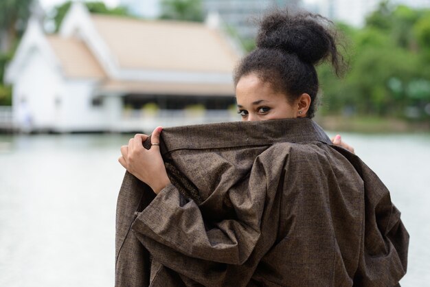 Porträt der jungen schönen afrikanischen Frau mit Afro-Haaren, die am Park draußen entspannen