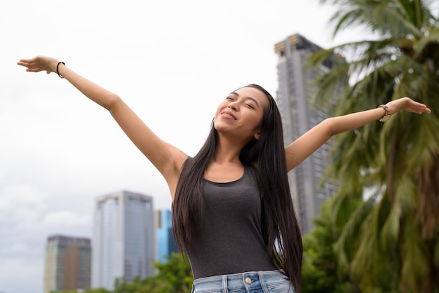 Porträt der jungen schönen asiatischen Frau, die am Park in Bangkok, Thailand entspannt