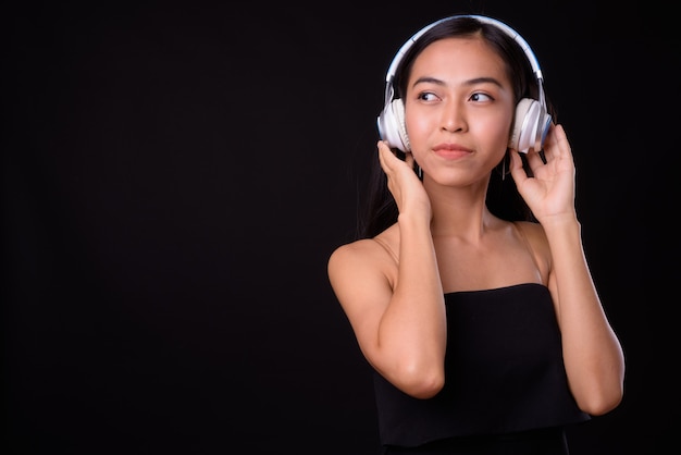 Porträt der jungen schönen asiatischen Frau, die beim Hören der Musik denkt
