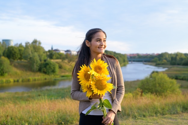 Porträt der jungen schönen asiatischen Frau gegen den entspannenden Blick auf den Fluss und das üppige grüne Feld