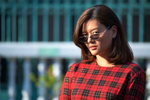 Porträt der jungen schönen asiatischen Geschäftsfrau, die Sonnenbrille in den Straßen draußen trägt