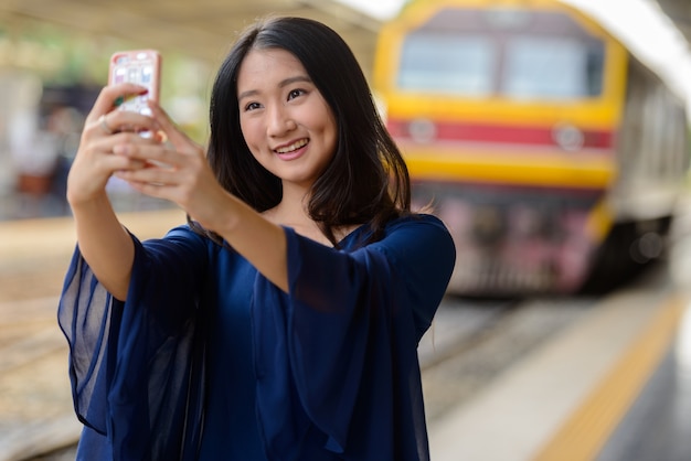 Porträt der jungen schönen asiatischen Touristenfrau am Hua Lamphong Bahnhof in Bangkok