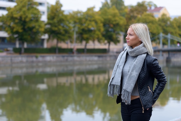 Porträt der jungen schönen blonden Skandinavierin, die sich am Fluss entspannt