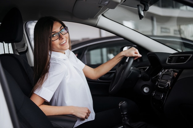 Porträt der jungen schönen Frau, die im Auto sitzt