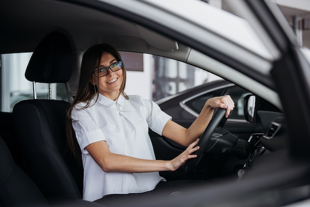 Porträt der jungen schönen Frau, die im Auto sitzt