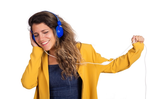 Porträt der jungen schönen Frau, die Musik mit blauen Kopfhörern auf Studio hört. Isolierter weißer Hintergrund.