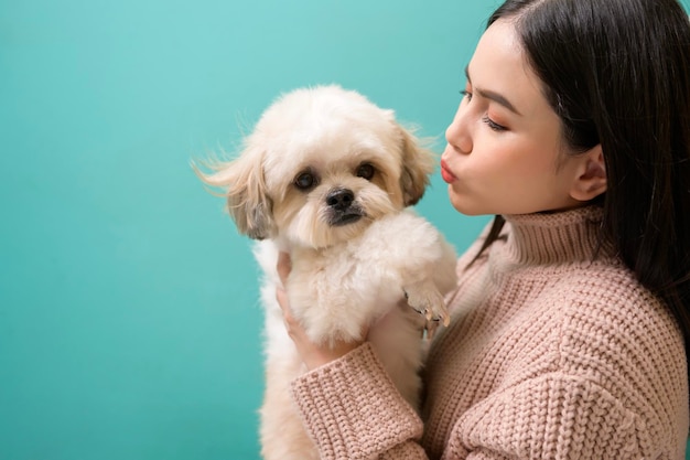 Porträt der jungen schönen Frau küsst und umarmt ihren Hund auf grünem Hintergrund