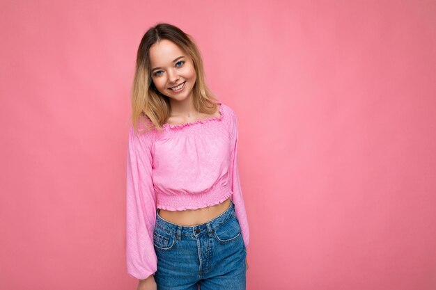 Porträt der jungen schönen lächelnden blonden Frau des Hippies in der trendigen rosa bauchfreien Bluse sexy