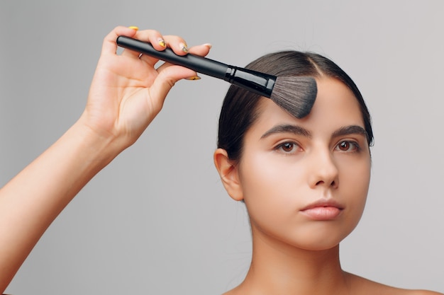 Porträt der jungen schönen positiven Frau mit nacktem Make-up und Pinsel.