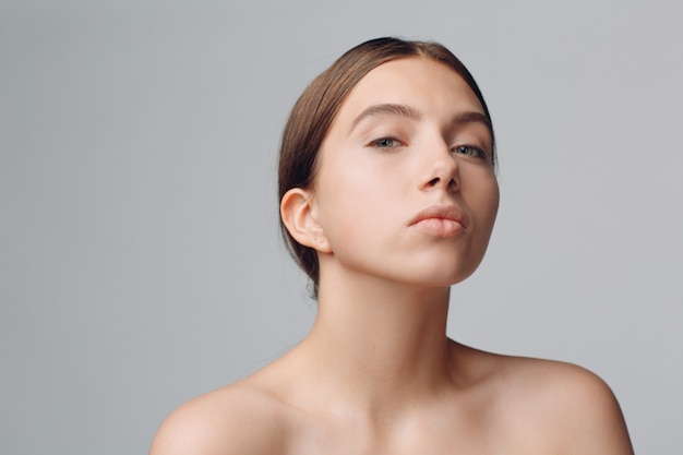 Porträt der jungen schönen positiven Frau mit nacktem Make-up.