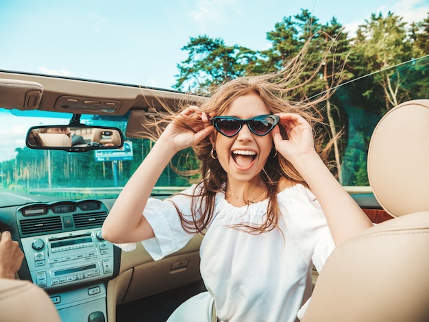 Porträt der jungen schönen und lächelnden Hippie-Frau im Cabrio-Auto