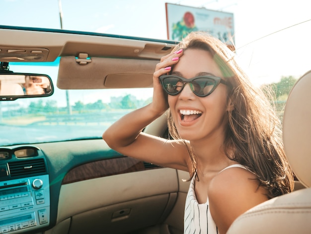 Porträt der jungen schönen und lächelnden Hippie-Frau im Cabrio-Auto