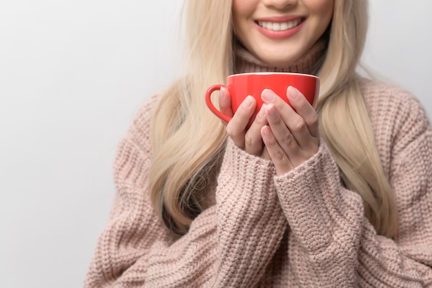 Porträt der kaukasischen jungen Frau, die den trinkenden Kaffee des Pullovers über weißem Hintergrund trägt