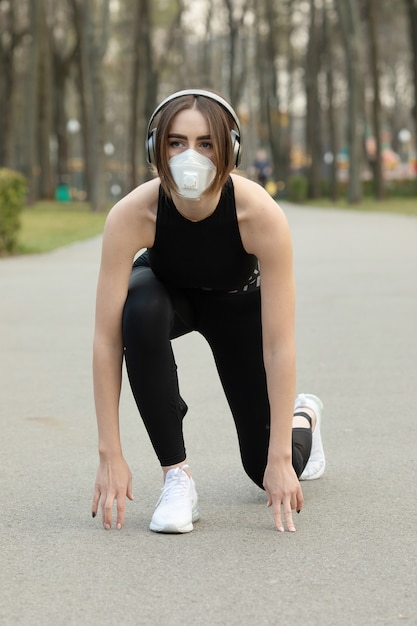 Porträt der kaukasischen sportlichen Frau, die eine medizinische Schutzgesichtsmaske beim Laufen im Park trägt. Das Corona-Virus oder Covid-19 verbreitet sich auf der ganzen Welt.