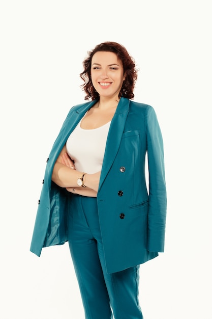 Porträt der lächelnden attraktiven Geschäftsfrau im blauen Anzug, der beim Stehen mit verschränkten Armen aufwirft