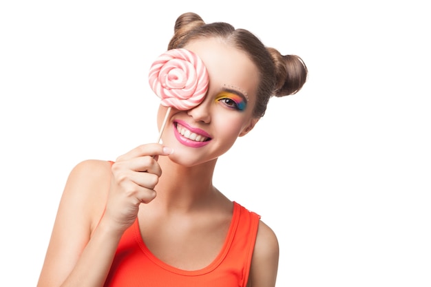 Porträt der lächelnden Brünette mit Brötchen, die das Auge mit lollipop.white background bedecken