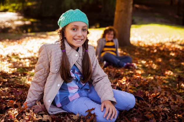 Porträt der lächelnden Geschwister, die im Herbst im Park sitzen