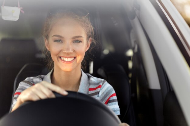 Porträt der lächelnden jungen Frau, die ihr Auto fährt