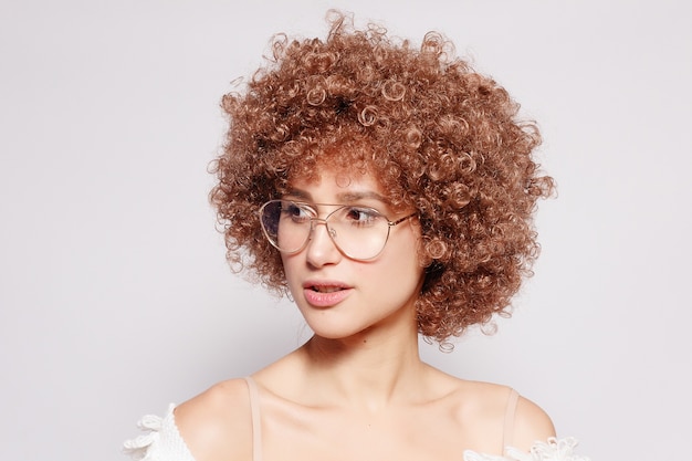 Porträt der lächelnden jungen schwarzen Frau. Porträt einer schönen jungen Frau mit Afroamerikaner-Afro-Haarschnitt und Glamour-Make-up. Studioaufnahme. Tragende Brille des attraktiven Mädchens.