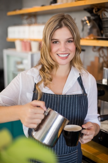 Porträt der lächelnden Kellnerin, die Tasse Kaffee macht