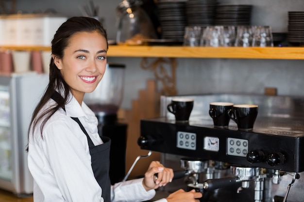 Porträt der lächelnden Kellnerin, die Tasse Kaffee macht