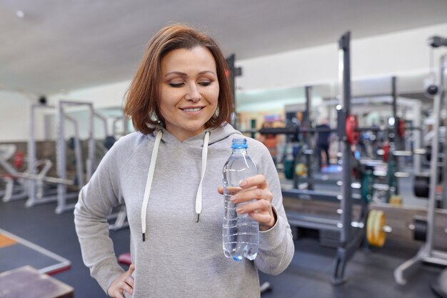 Porträt der lächelnden reifen Frau mit Flasche Wasser