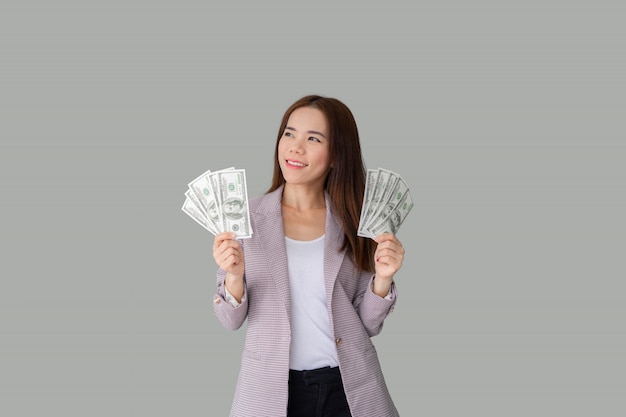 Porträt der lächelnden schönen asiatischen Frau, die viel Geld Banknoten hält