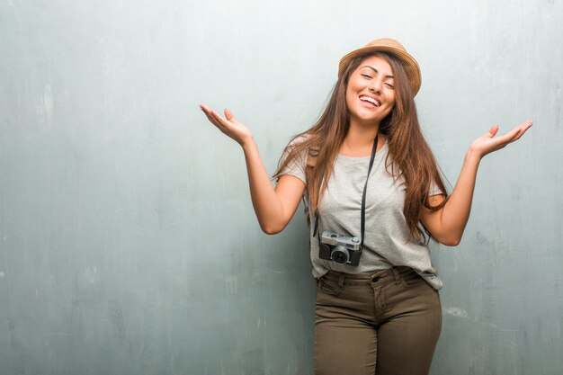 Porträt der lateinischen Frau des jungen Reisenden gegen eine Wand, die Spaß lacht und hat und entspannt und nett ist, fühlt sich überzeugt und erfolgreich