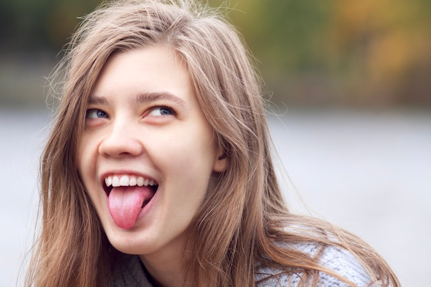 Porträt der lustigen verrückten verrückten jungen Frau, lächelndes Teenager-Mädchen, lachend mit ihrer Zunge aus