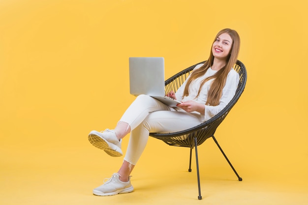 Foto porträt der modernen frau mit laptop auf stuhl