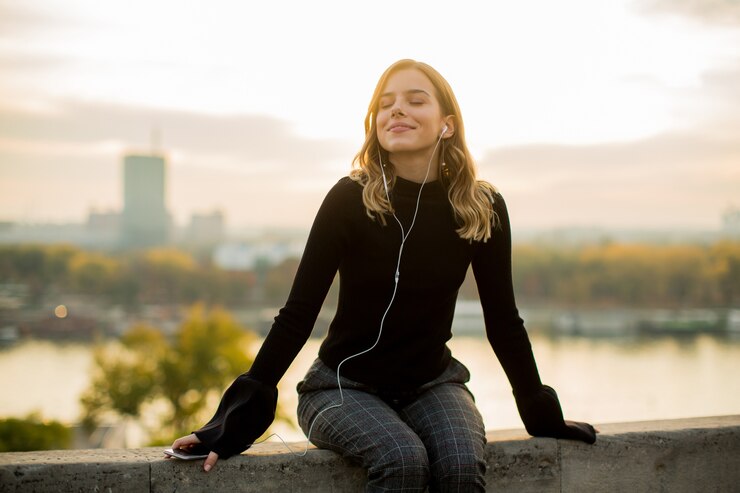 Foto porträt der modischen hörenden musik der jungen frau vom smartphone im freien bei sonnenuntergang