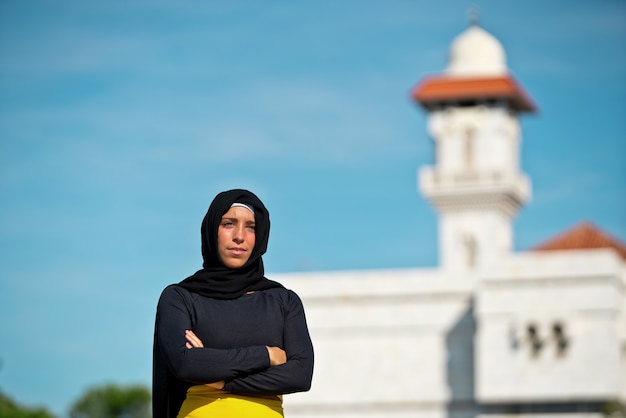 Porträt der muslimischen Frau, die einen Hijab trägt, der mit Moscheehintergrund lokalisiert wird. Horizontale Ansicht der arabischen Frau im Freien. Muslimische Frauen und kulturelles Konzept.