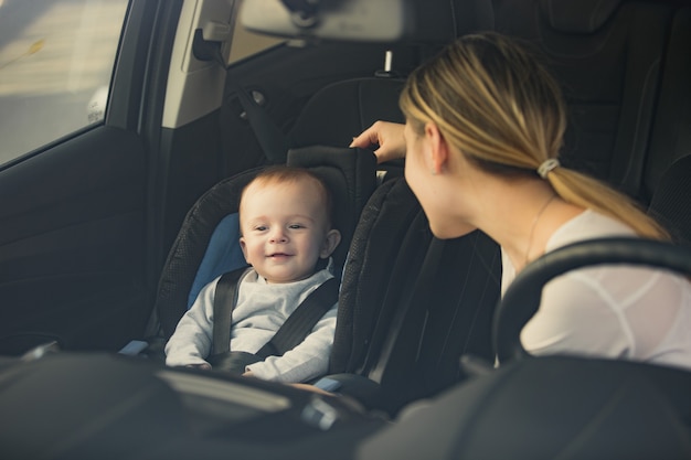 Porträt der Mutter, die das Baby betrachtet, das auf dem Vordersitz des Autos sitzt