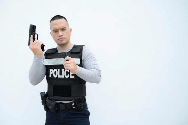 Porträt der Polizei hält Waffe in der Hand auf weißem Hintergrund. Hübscher asiatischer Polizist