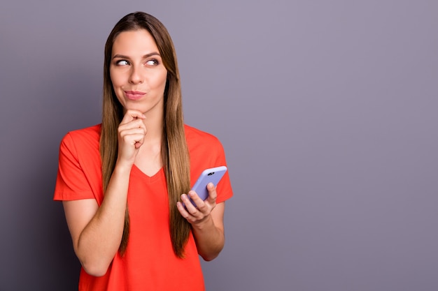 Foto porträt der positiven brünetten dame im roten t-shirt, das gegen die lila wand mit telefon aufwirft