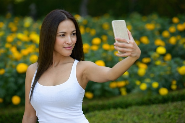 Porträt der schönen asiatischen Frau, die am Park draußen entspannt