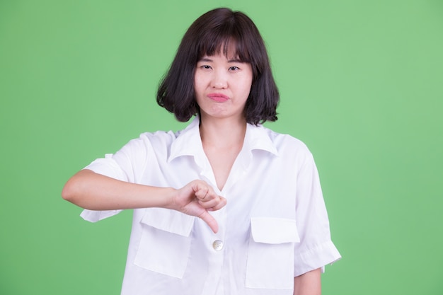 Porträt der schönen asiatischen Geschäftsfrau mit kurzen Haaren gegen Chroma Key oder grüne Wand