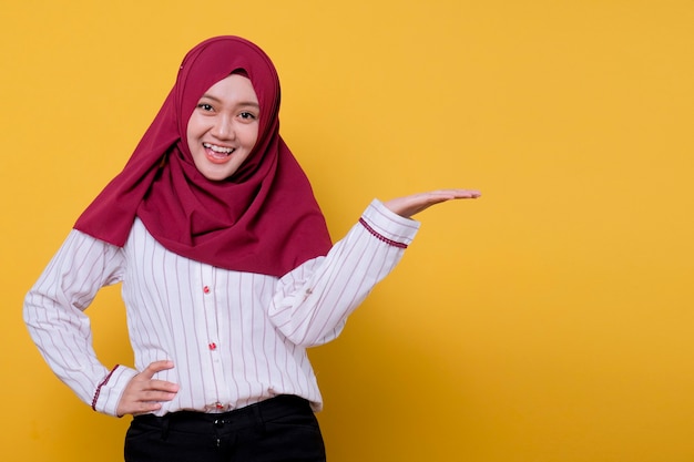 Porträt der schönen Frau, die Hijab trägt, der etwas auf ihrer Hand zeigt, schaut lächelnden Ausdruck