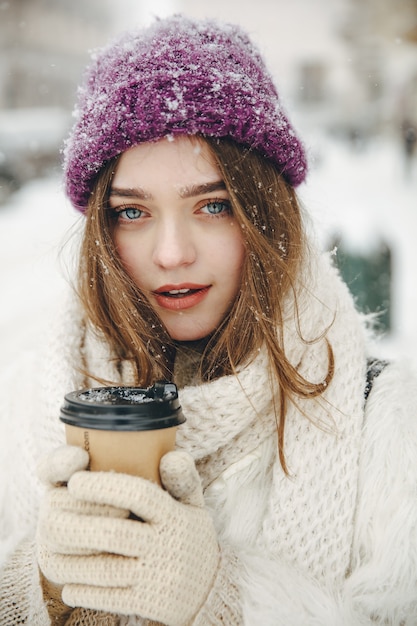 Porträt der schönen Frau, die warme Kleidung trägt und heißen Kaffee trinkt